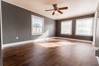 An empty living room with wood floors and a ceiling fan